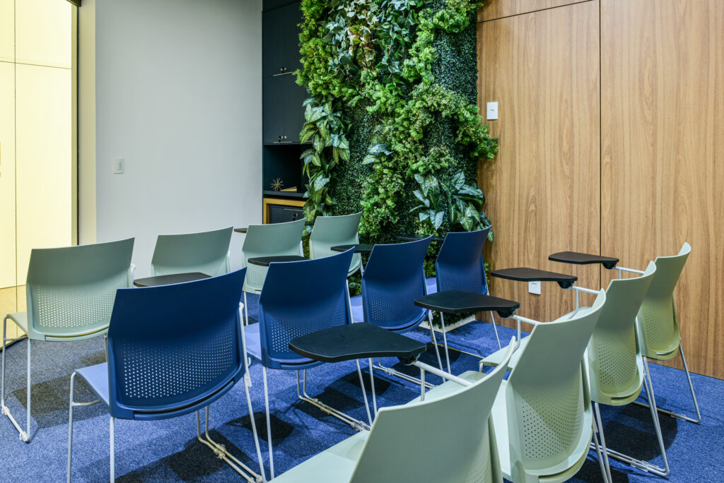 Sala de treinamento com cadeiras com prancheta e jardim vertical